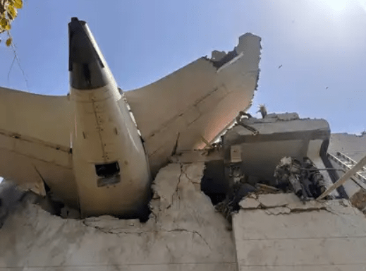 Plane crashes into residential building in Ahmedabad, with aircraft tail section embedded in the structure.